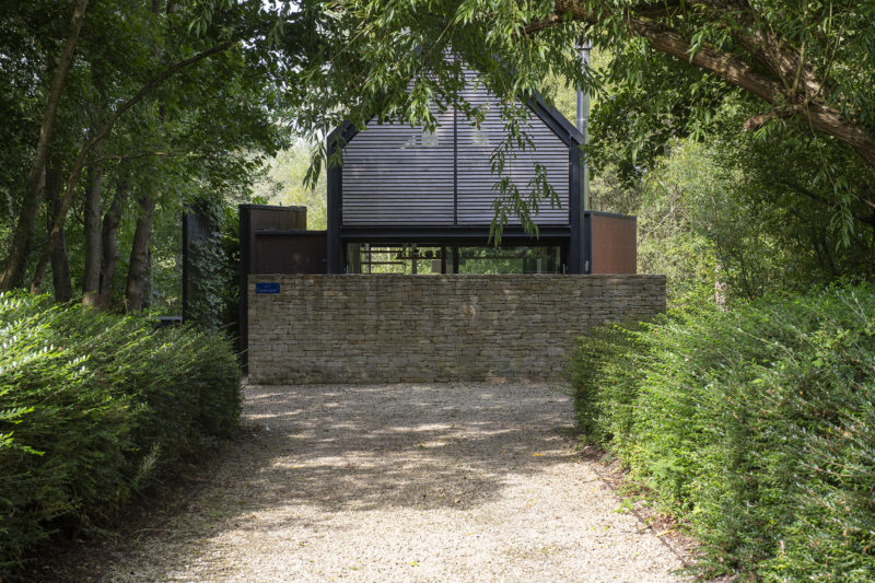 A gravel path, flanked by hedges, leads to Island Lodge, our charming holiday home that is nestled in a private eco-estate in the Cotswolds